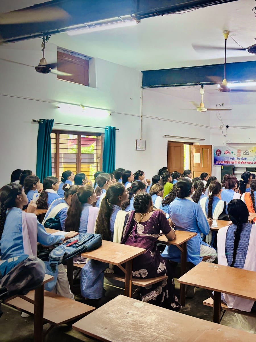 Students with long braids seated at wooden benches, facing the front of a classroom at A.P. Sen Memorial Girls College, Lucknow