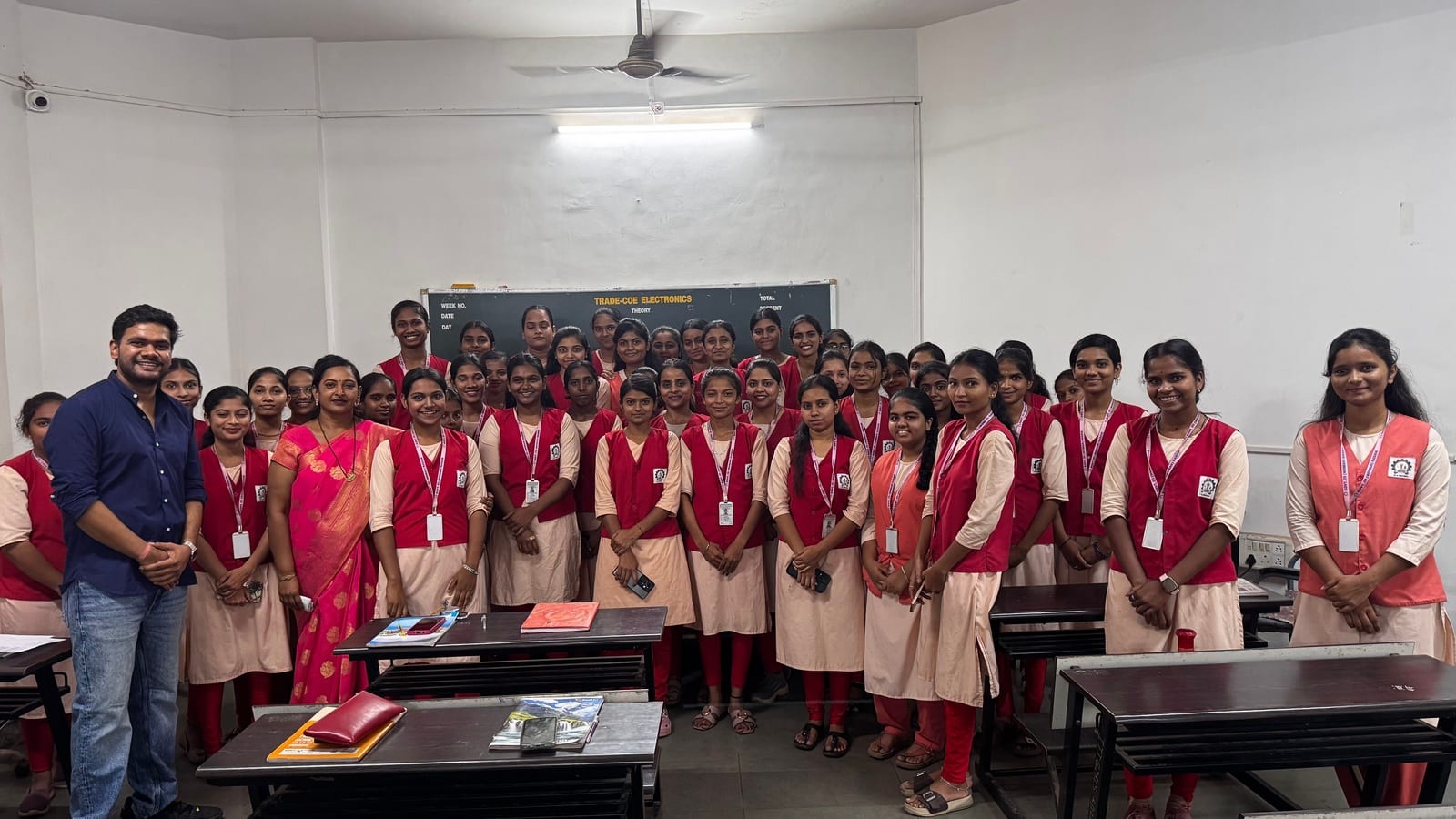 A large group of students in uniform standing with a facilitator and staff in a classroom at a government ITI