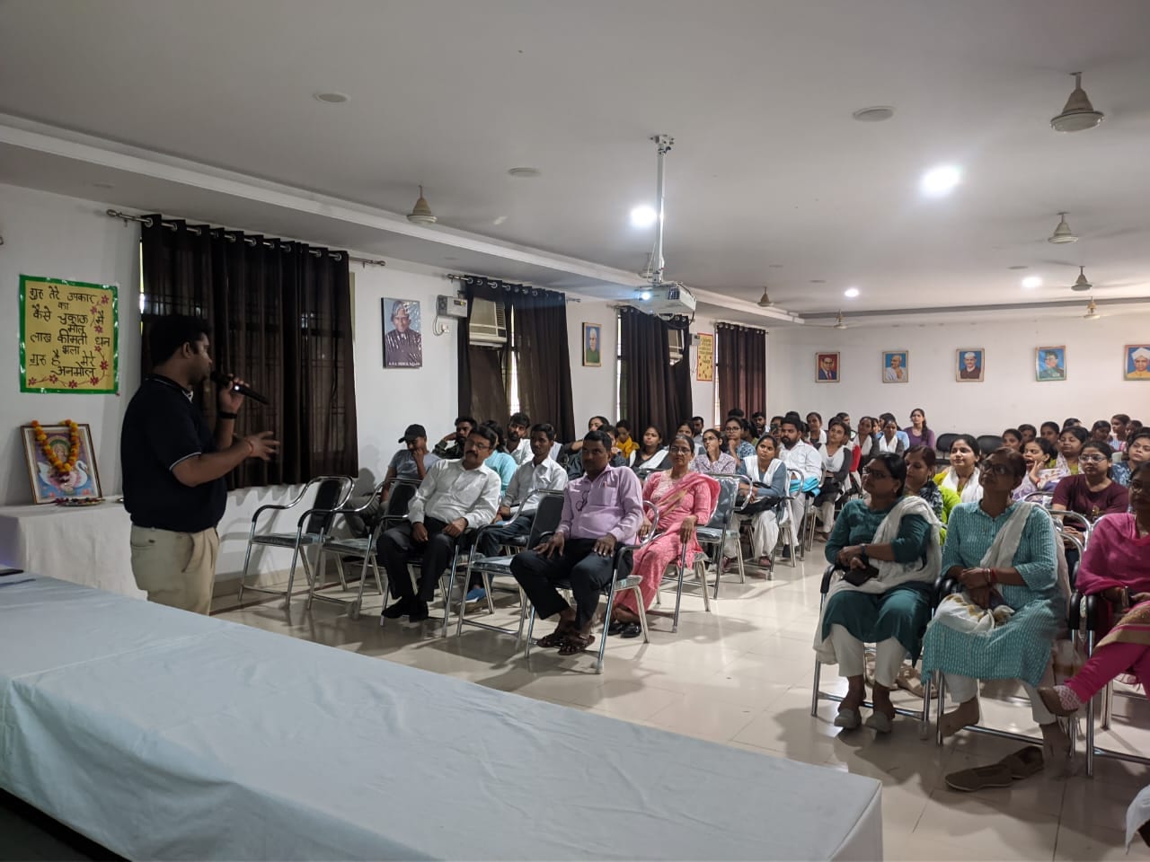 Educators and staff seated for an AI capacity-building session, facilitator presenting with a handheld microphone.
