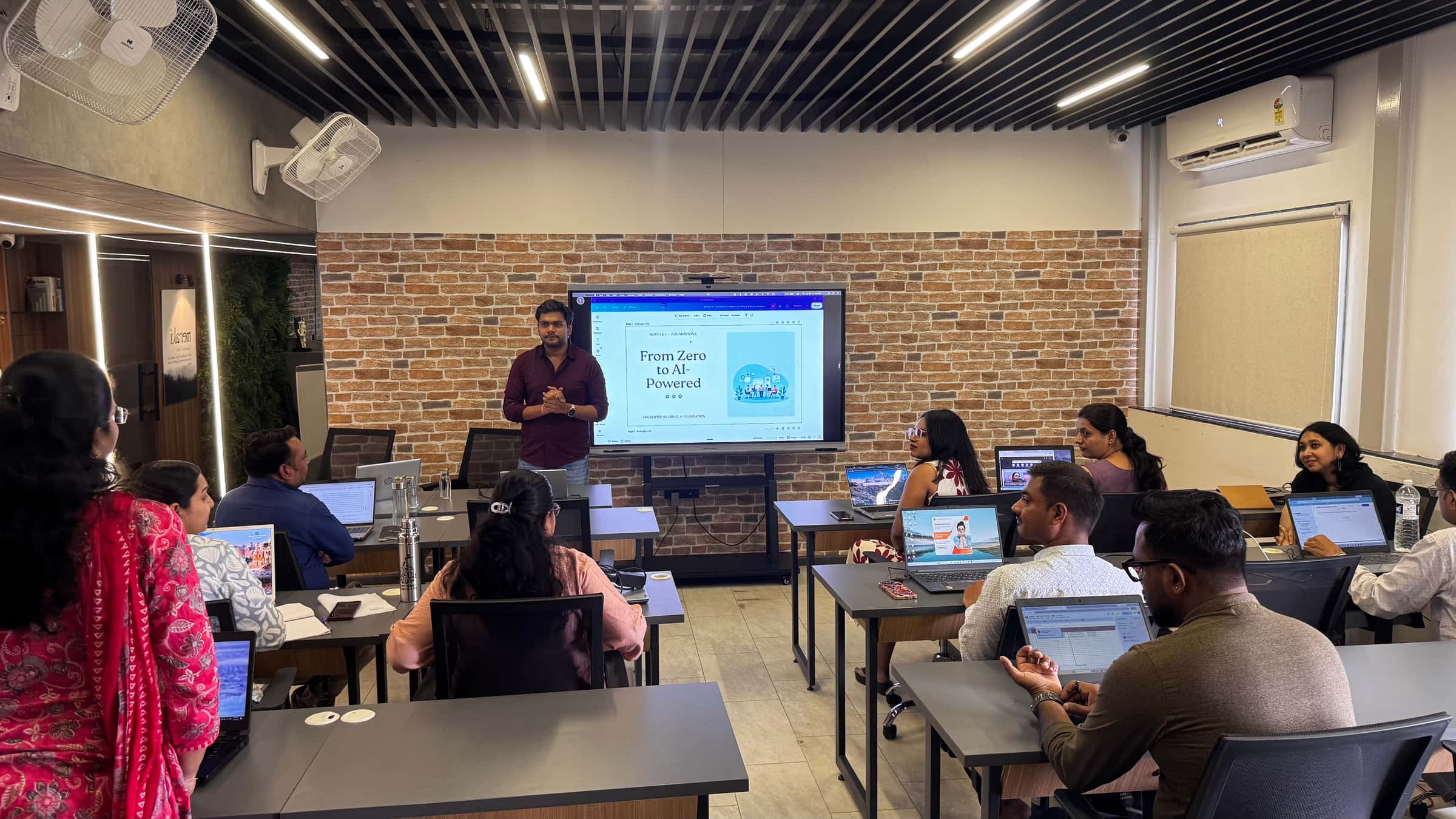 A QriusAI facilitator leading a Catalyst session, presenting a 'From Zero to AI-Powered' program overview to a room of nonprofit professionals on laptops.
